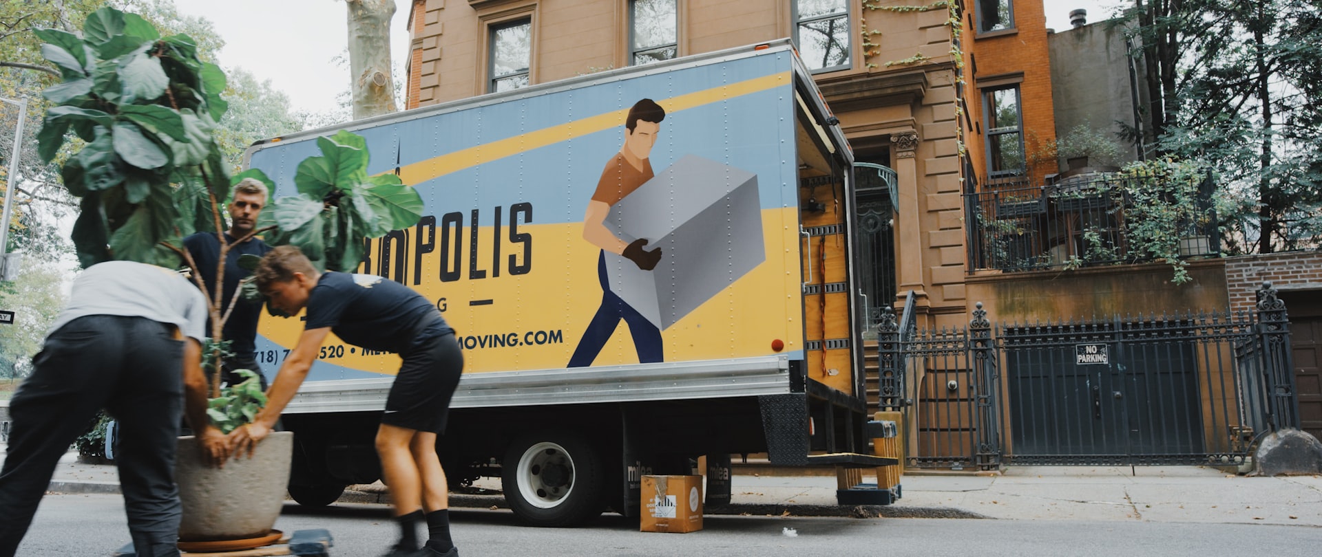 Professional movers loading furniture into a moving truck outside a New York brownstone