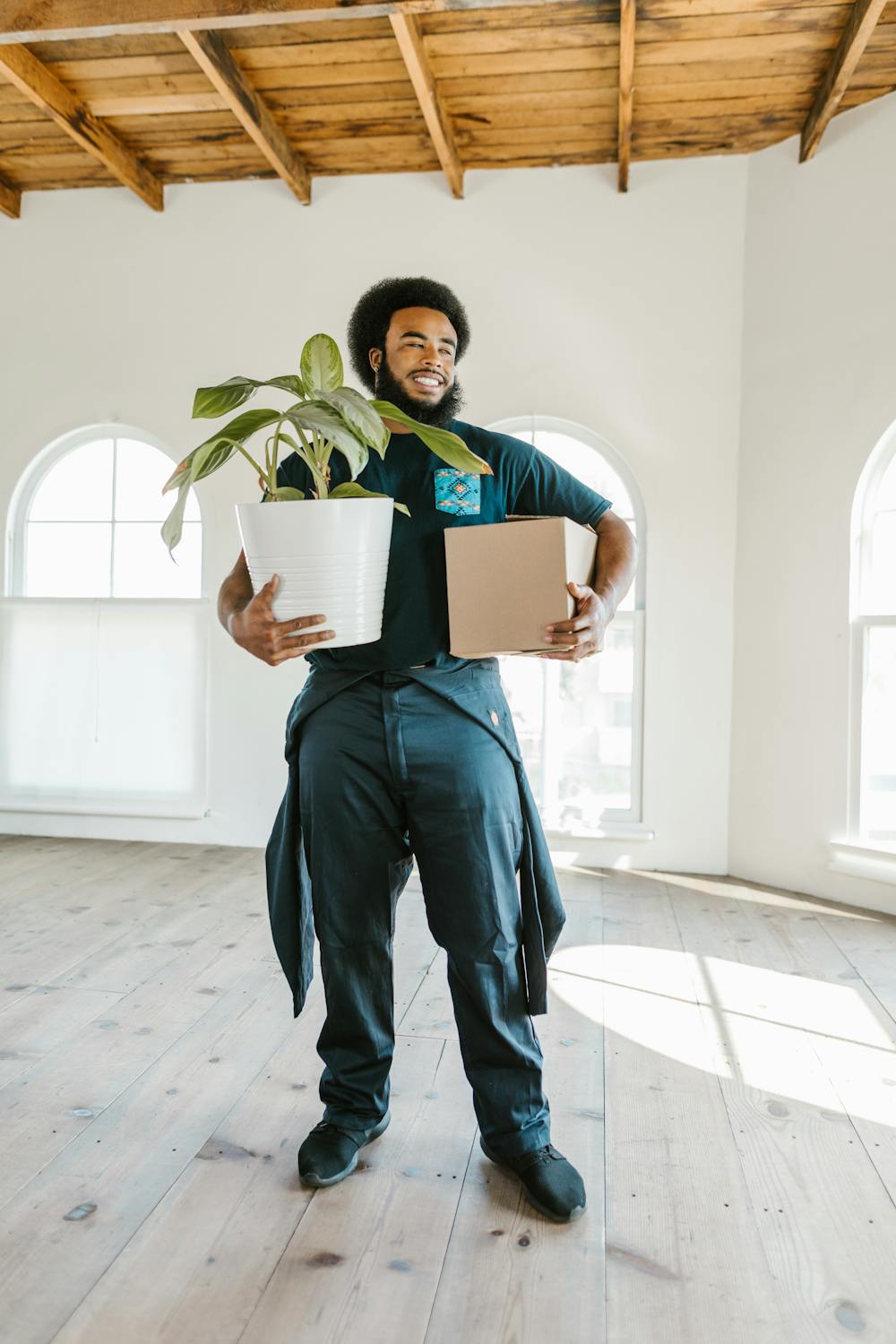 Uniformed mover carrying a box and houseplant into a customer's new home