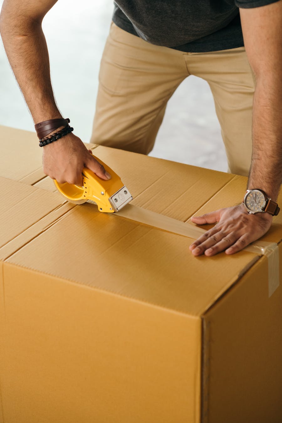 Professional mover sealing a moving box with packing tape